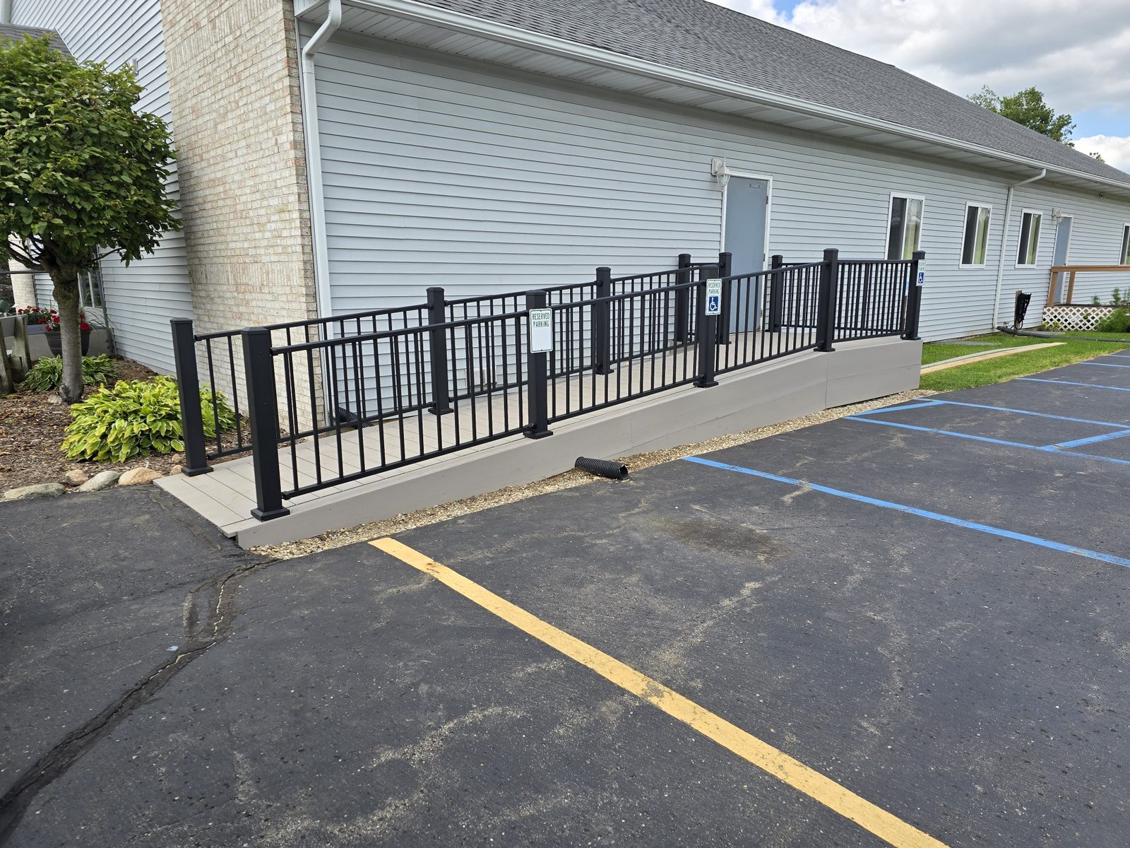 Finished accessible ramp with composite decking and black aluminum railings along a building in Southwest Michigan