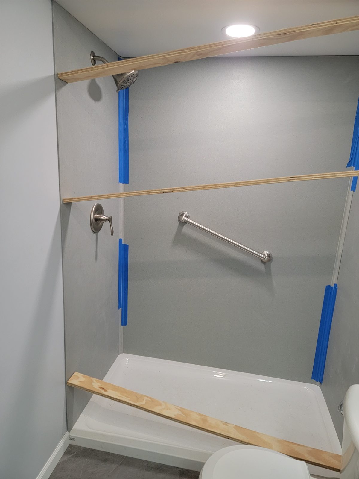 Shower wall panels and a grab bar being installed in a basement bathroom in Southwest Michigan