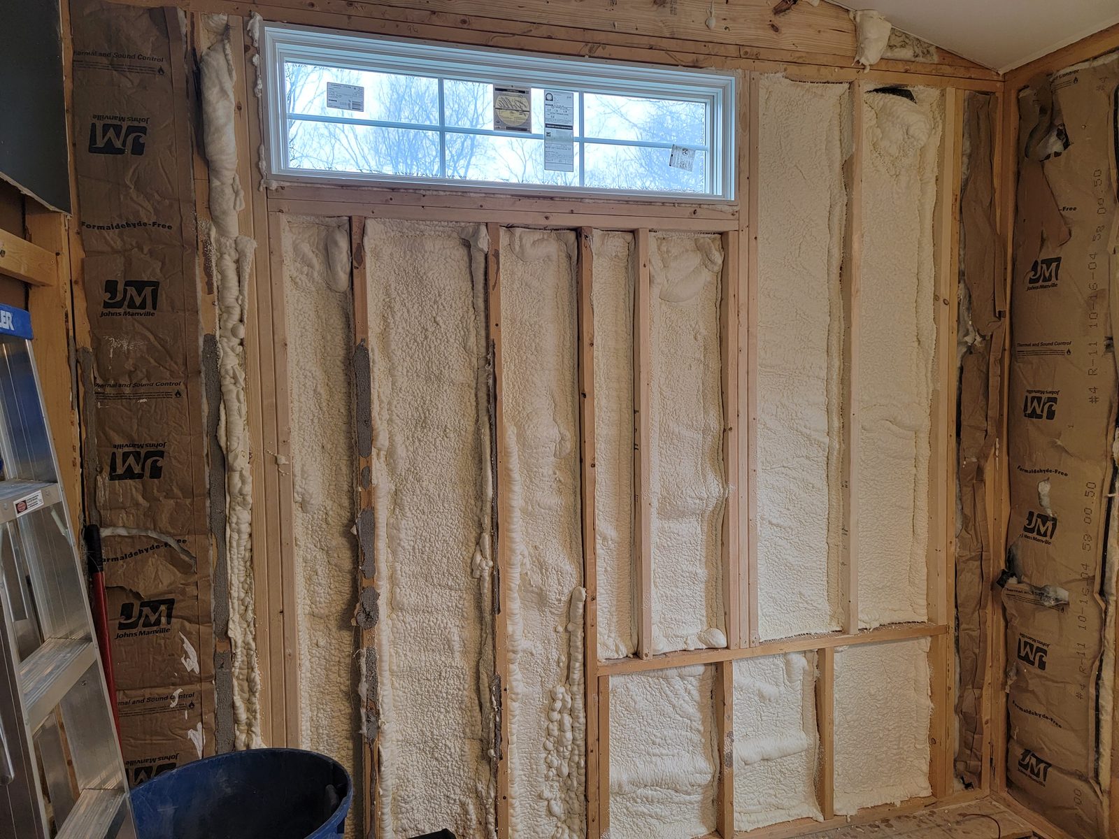 Spray foam insulation in a bathroom wall under a new transom window in Southwest Michigan
