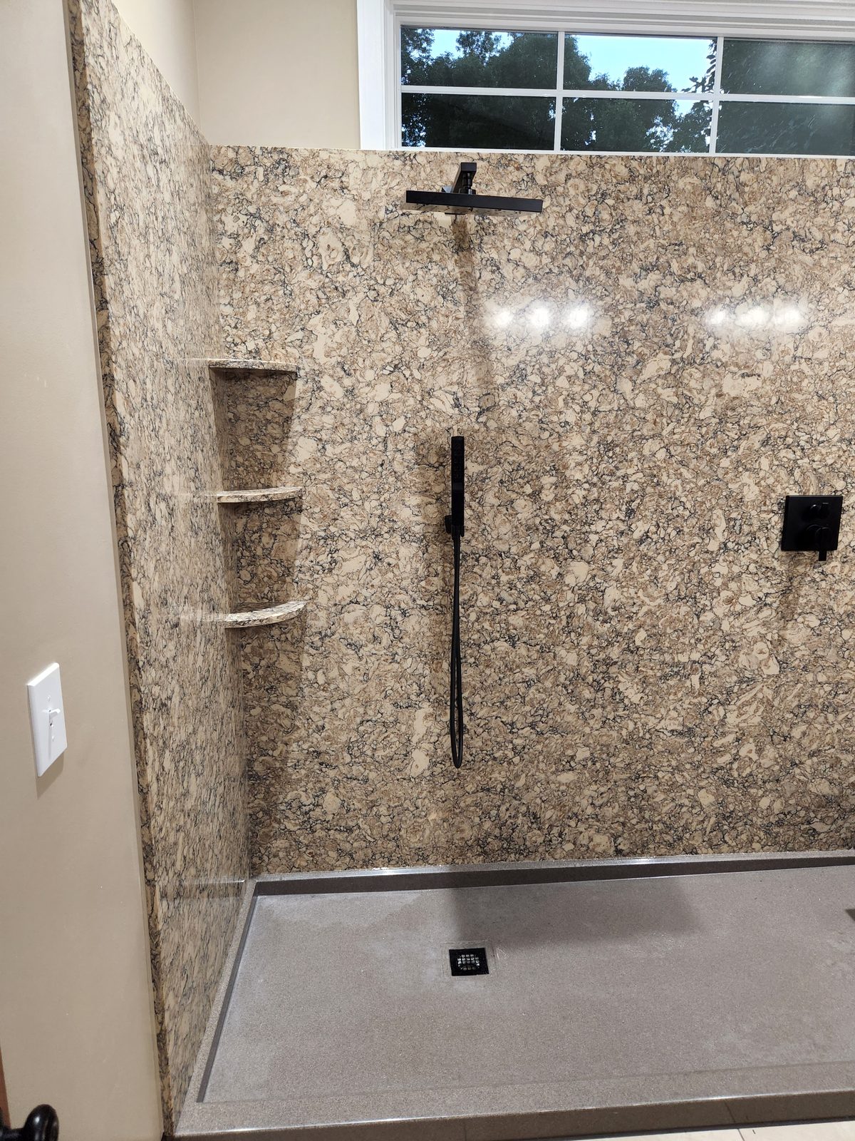Walk in shower with a black rain head, handheld sprayer and granite look panels in Southwest Michigan