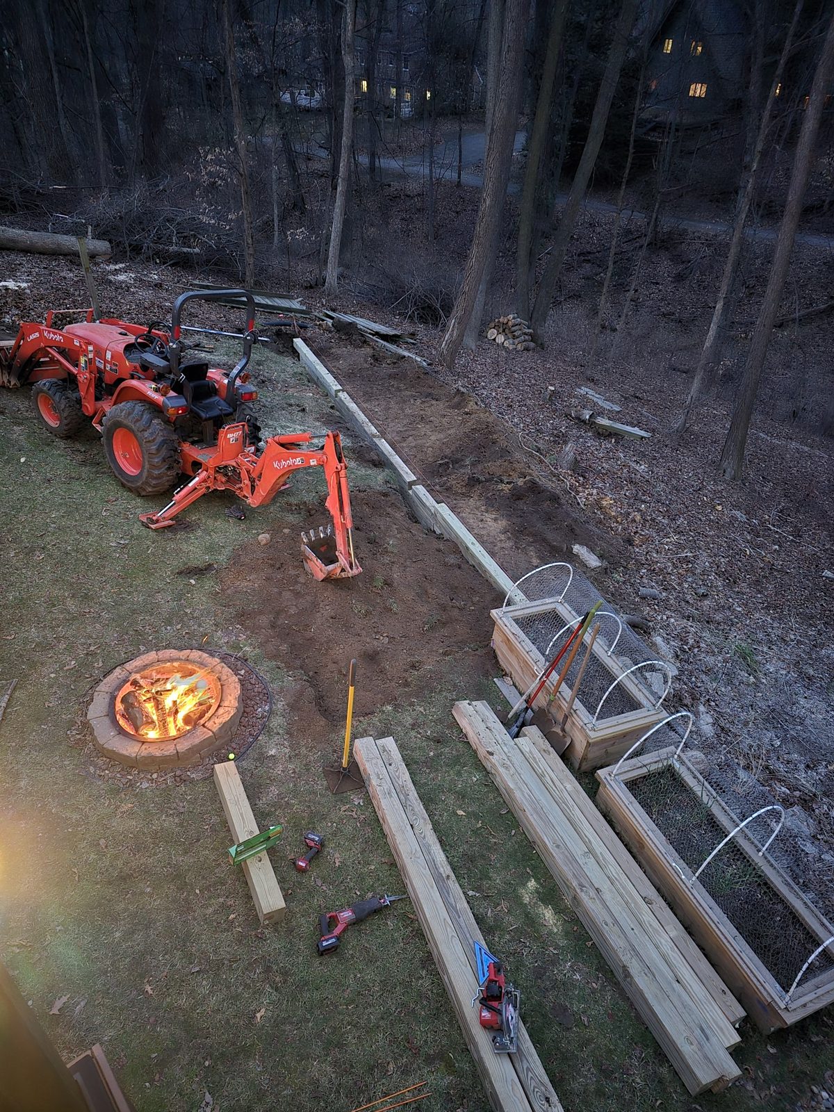 Equipment and pressure treated timbers staged for a retaining wall in a wooded backyard in Southwest Michigan