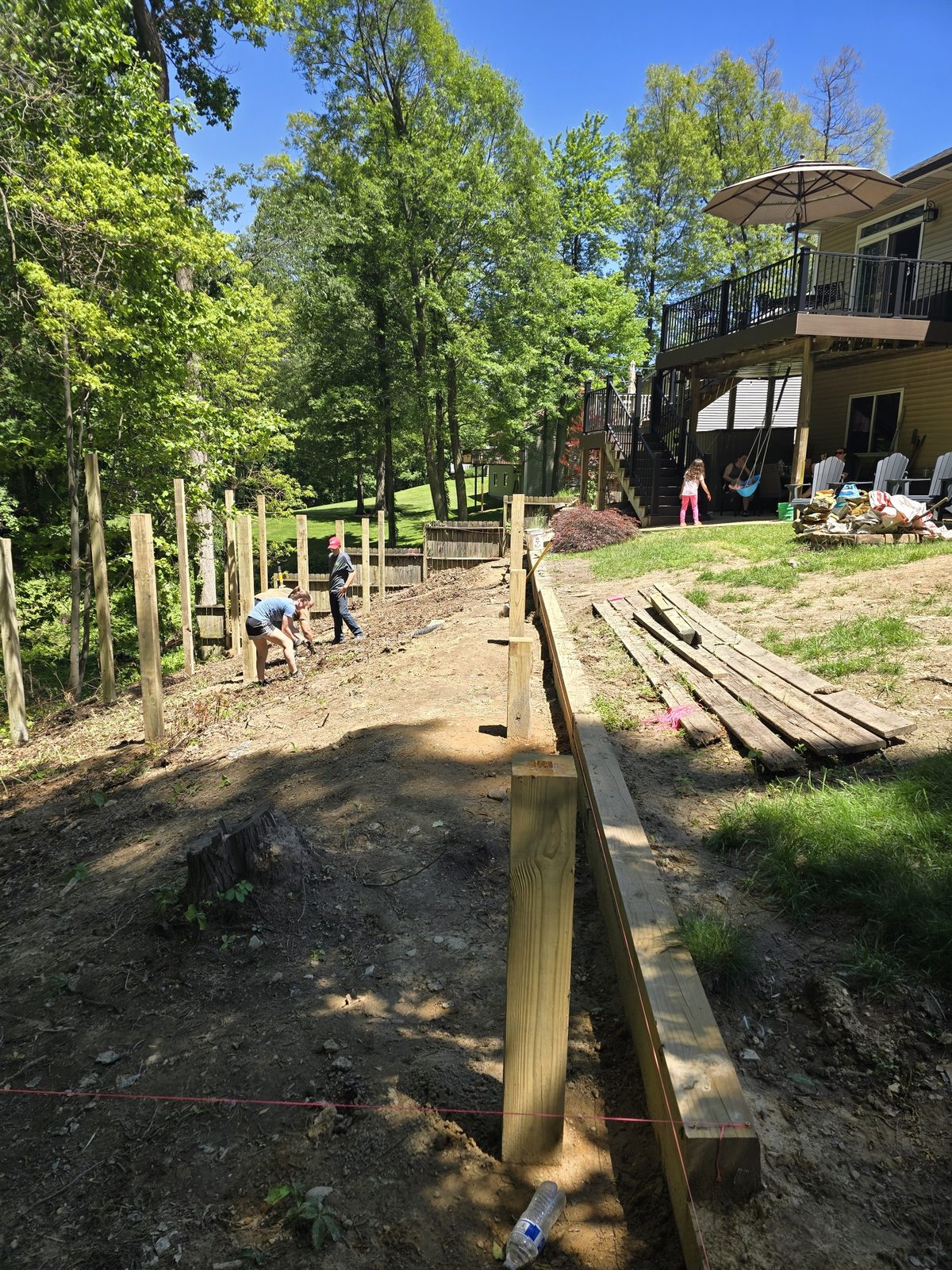 Timber retaining wall being built along a sloped backyard in Southwest Michigan