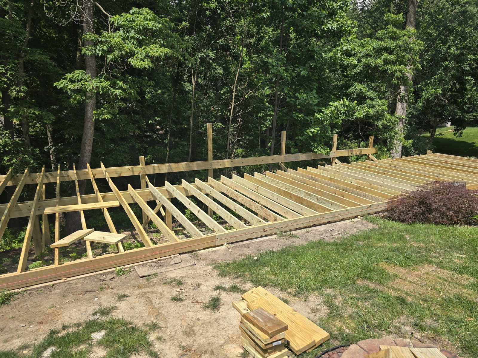 Deck joists framed across a backyard beside existing stairs in Southwest Michigan