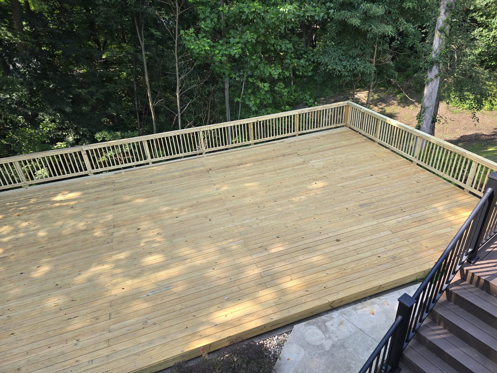 Finished ground level deck with railings tied into existing stairs in Southwest Michigan
