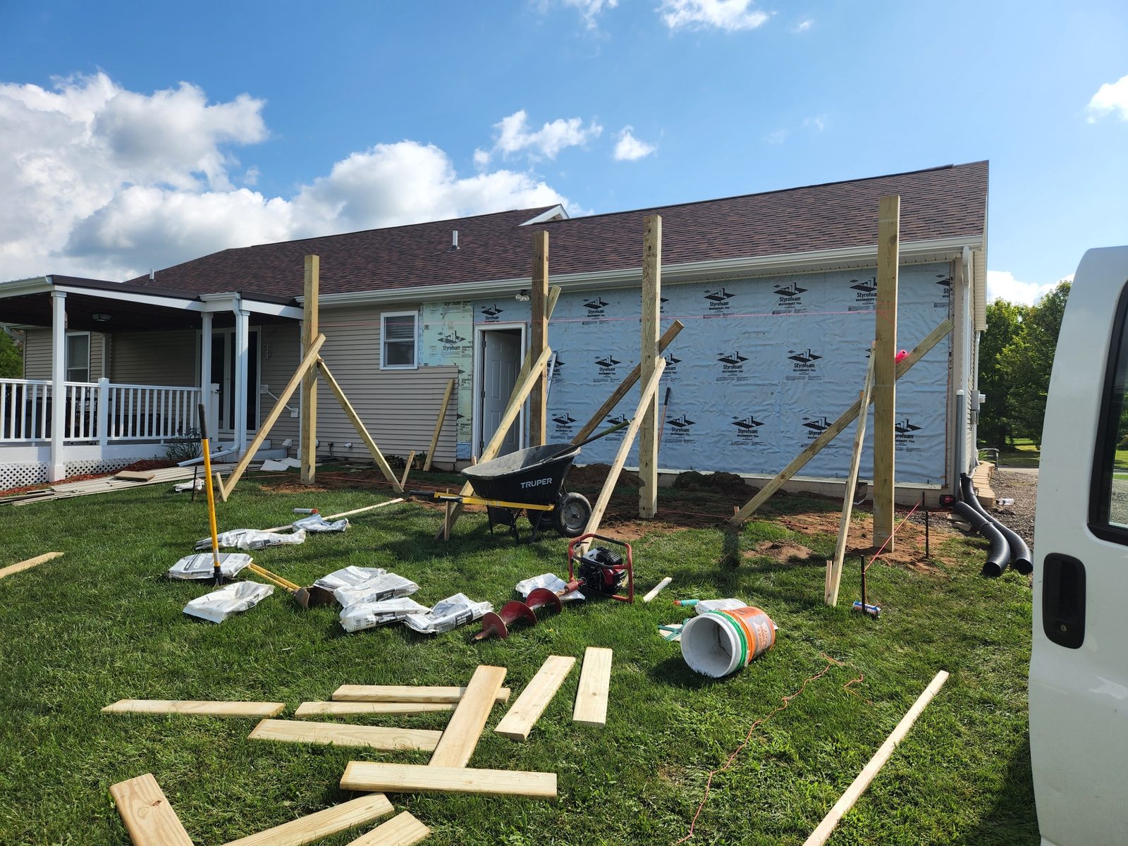 Concrete footing forms and posts set along a house for a garage addition in Southwest Michigan