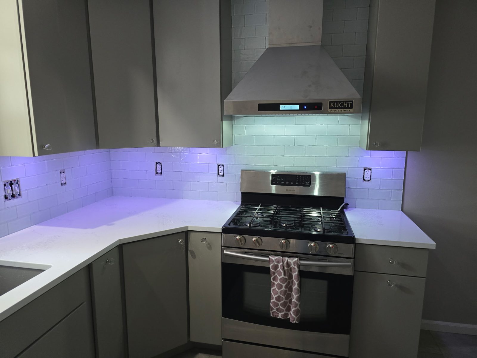 Completed kitchen remodel in Plainwell, MI — gas range under a stainless pro-style hood with full-height subway tile backsplash and quartz counters
