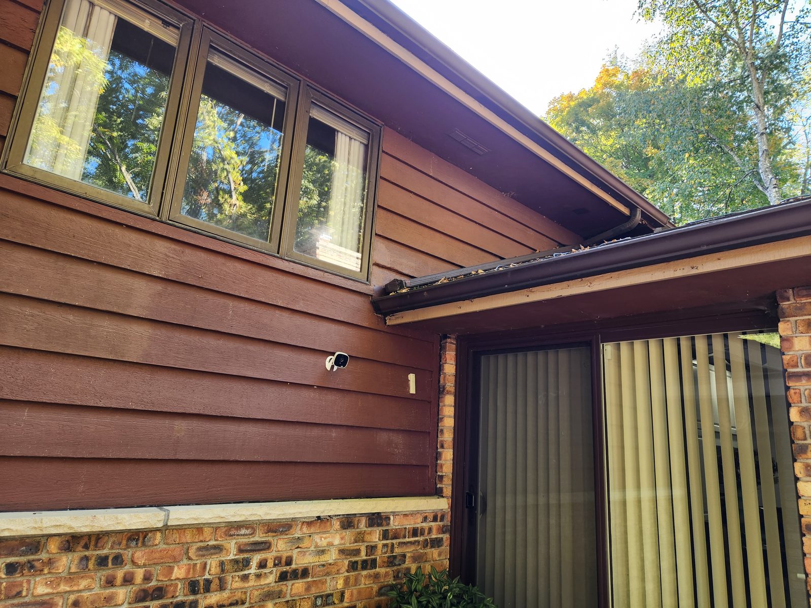 Brown wood siding and roof edge on a home in Southwest Michigan before exterior repairs