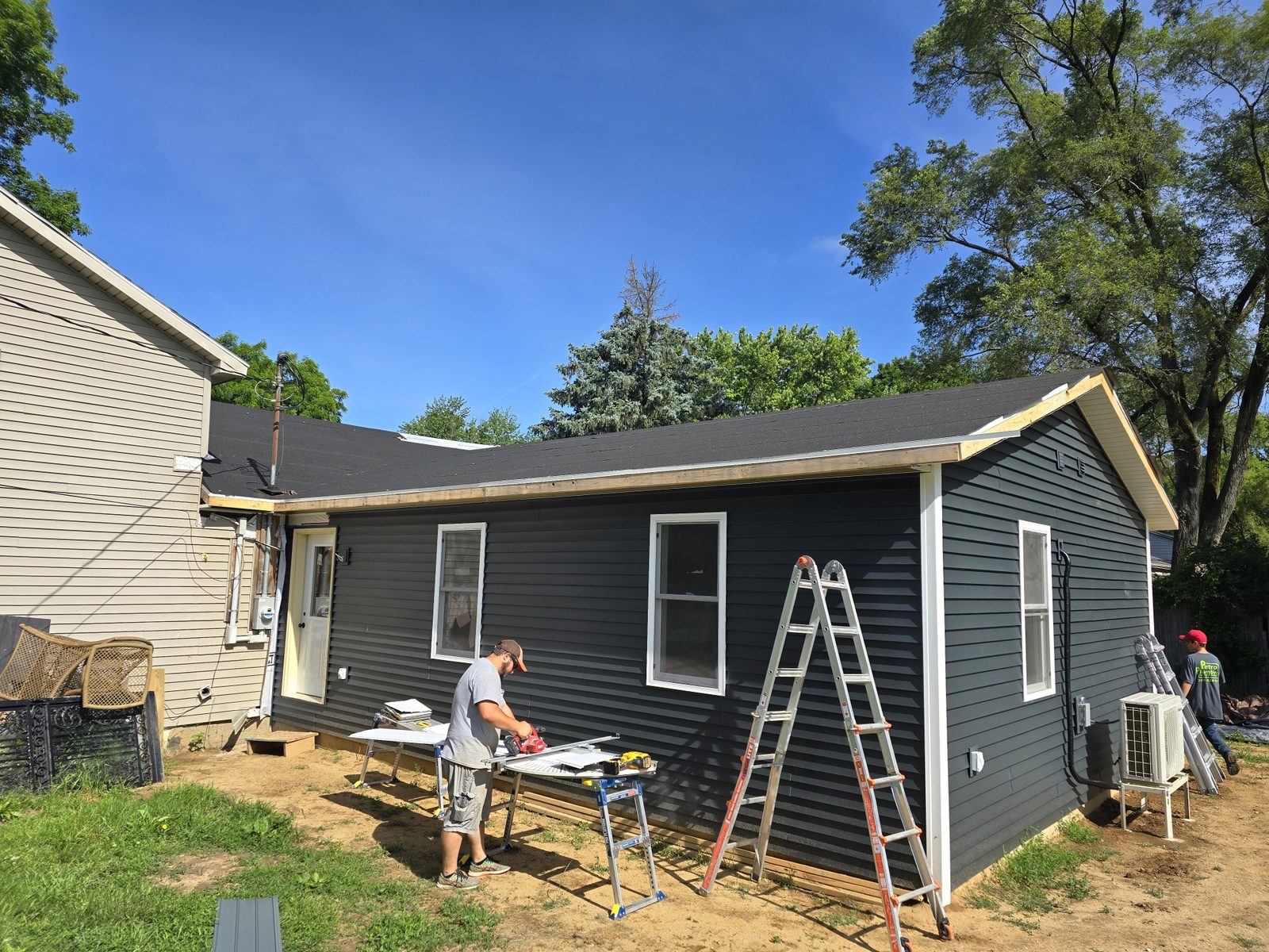 Dark blue vinyl siding being installed on a finished room addition in Southwest Michigan