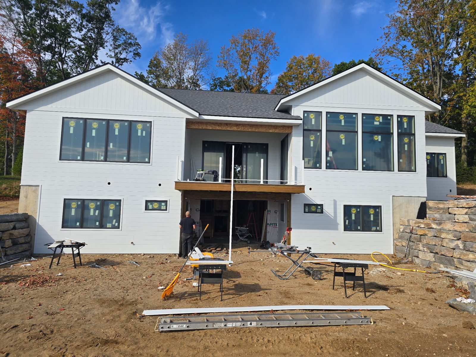 Rear elevation of a new-construction home in West Michigan with crisp white lap and board-and-batten siding and a walkout balcony